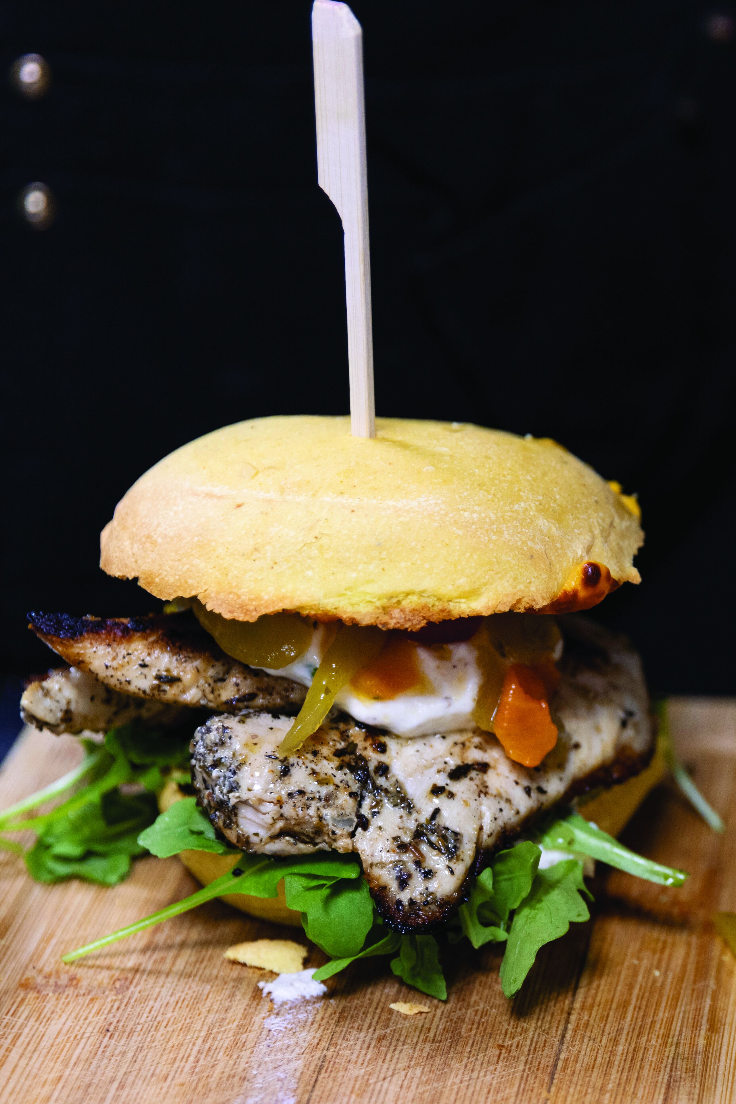 A sandwich with a toothpick on a wooden surface.