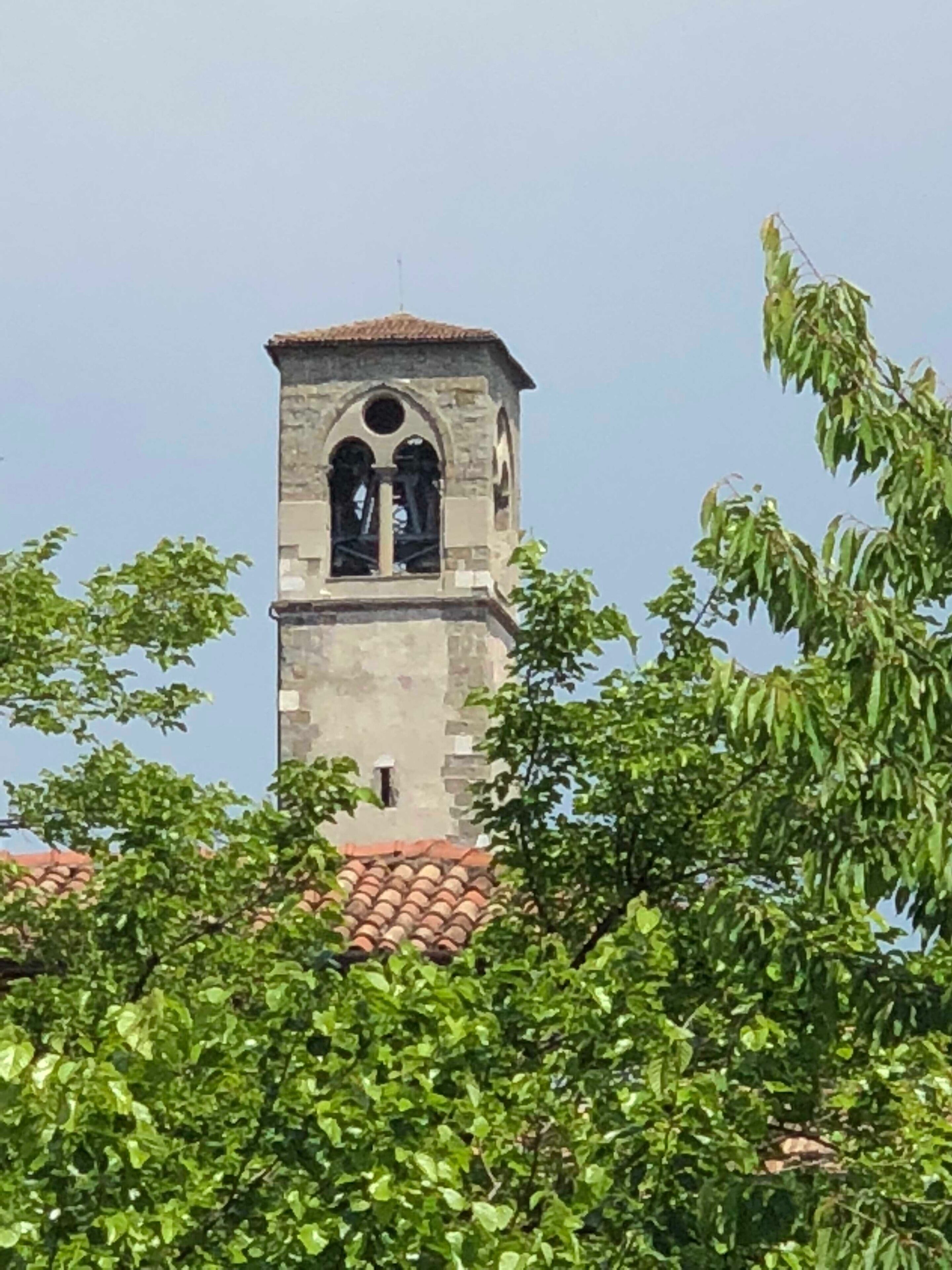 Una torre de piedra con ventanas de arco y una campana.