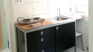 Una cocina con armarios negros, un lavamanos de acero inoxidable y una ventana con persianas.