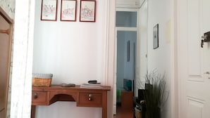 Un pasillo con un escritorio de madera, tres cuadros en la pared y una planta en maceta.