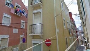 Una calle estrecha flanqueada por edificios, con balcones y barandillas, y una señal de prohibido el paso.