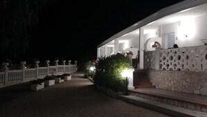 Un edificio moderno con fachada de piedra, una cerca blanca y una entrada bien iluminada.