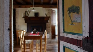 A dining area with a wooden table and chairs, a fireplace, and a painting on the wall. - The Music Country House, between Asolo, the Prosecco hills and Monte Grappa (Castelcies)