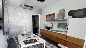 A modern kitchen with a white dining table, clear chairs, and a microwave.