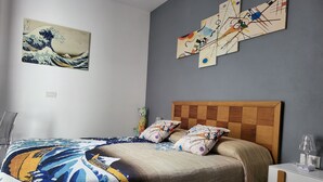 A modern bedroom with a wooden headboard, a bed with patterned bedding, a cat-shaped pillow, and abstract art on the walls.