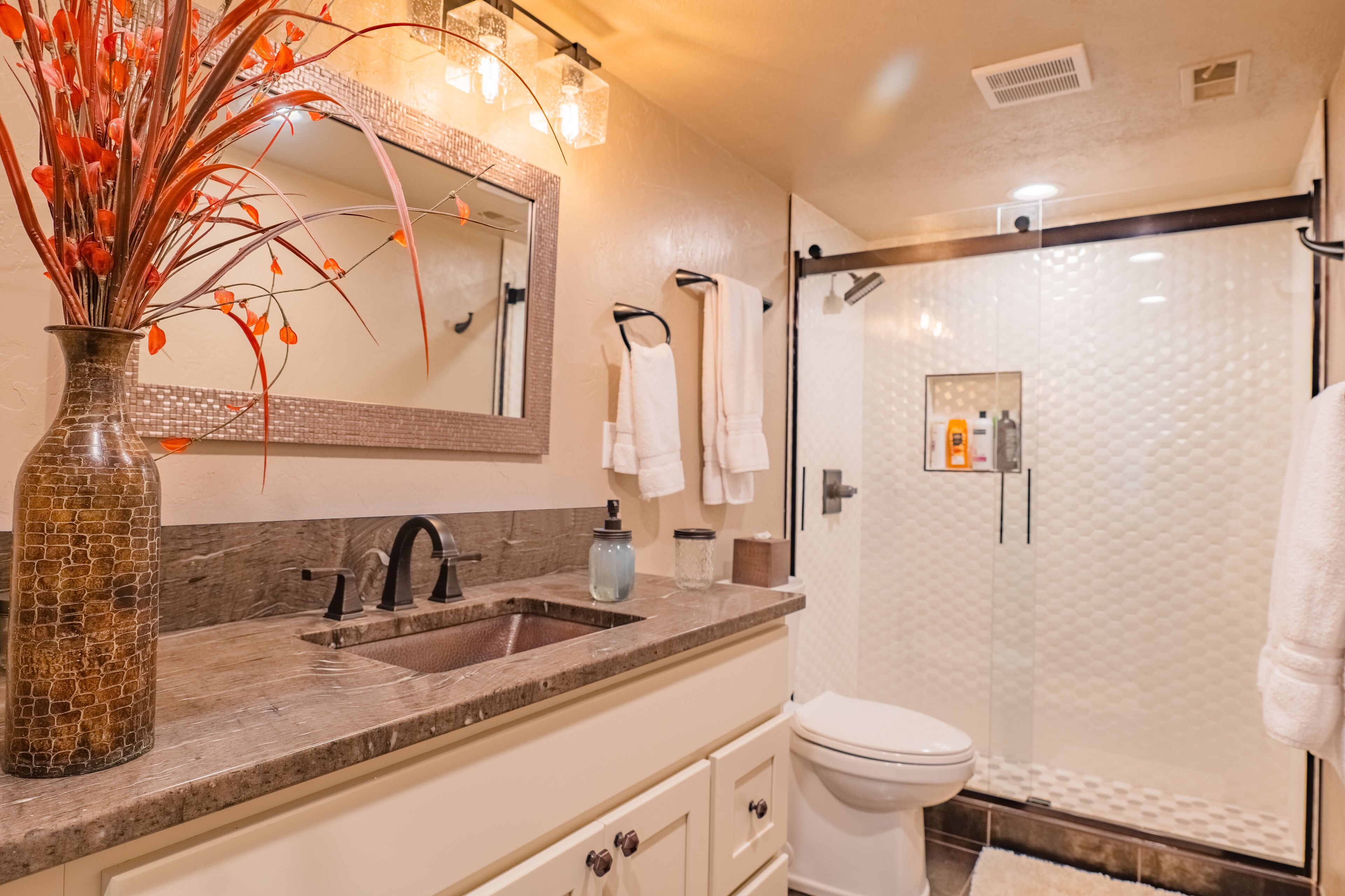 Une salle de bain moderne avec un comptoir en marbre, une douche en verre et un grand miroir.