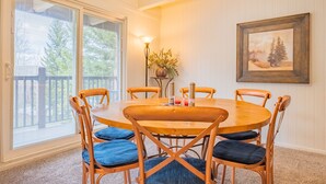 A dining area with a round wooden table, six wooden chairs with blue cushions, a floor lamp, and a framed picture on the wall. - Copper Moose on Main Street Awaits You!! (Breckenridge)
