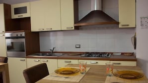 A kitchen with light-colored cabinets, a stainless steel oven, a sink, and a stove. - Shardan Guest House (Alghero)