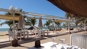 A beachside restaurant with outdoor seating, tables, and umbrellas, overlooking the sea. - BEAUTIFUL VILLA WITH SWIMMING POOL, RESIDENCE "SAFARI VILLAGE" WITH PRIVATE BEACH 100M (Unknown)