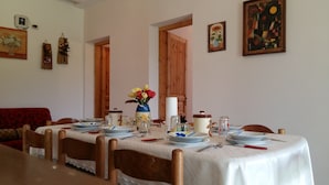 Ein Esszimmer mit Tisch für vier Personen, Holzsesseln, einer Blumenvase und Bildern an den Wänden.