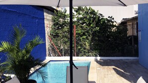 Zona esterna con tavolo e sedie, piscina e parete blu.