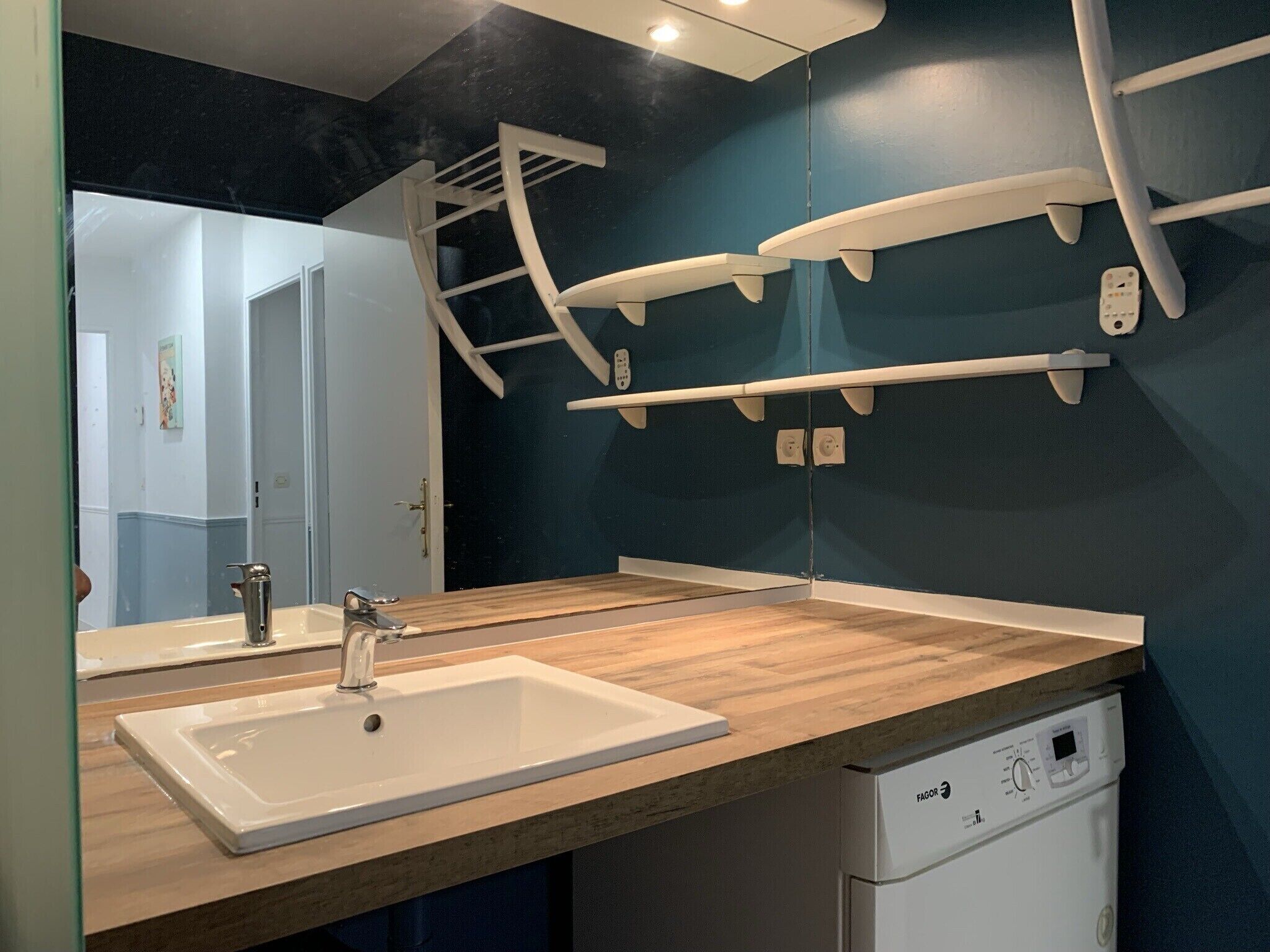 Une salle de bain avec un plan de toilette en bois, deux éviers, un miroir et un lave-vaisselle blanc.