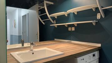 Une salle de bain avec un plan de toilette en bois, deux éviers, un miroir et un lave-vaisselle blanc.