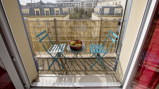 A balcony with two blue chairs, a small round table, and a basket of fruit. - Disneyland Paris 3 minutes away, sleeps 8, 2 bedrooms. (Chessy)