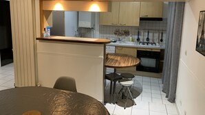 A compact kitchen with a wooden countertop, two stools, a small dining table, and a built-in oven. - Disneyland Paris 3 minutes away, sleeps 8, 2 bedrooms. (Chessy)