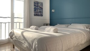 A hotel room with a large bed, a view of the city, and a word cloud artwork on the wall. - Disneyland Paris 3 minutes away, sleeps 8, 2 bedrooms. (Chessy)