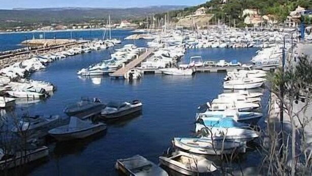 Una marina con numerosos barcos amarrados, rodeada de colinas y un cielo despejado.