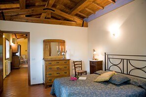Une chambre avec un plafond en bois, un lit avec une literie bleue, une commode en bois et un miroir.