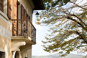 Un edificio con un balcone, un lampione e un albero con foglie autunnali.