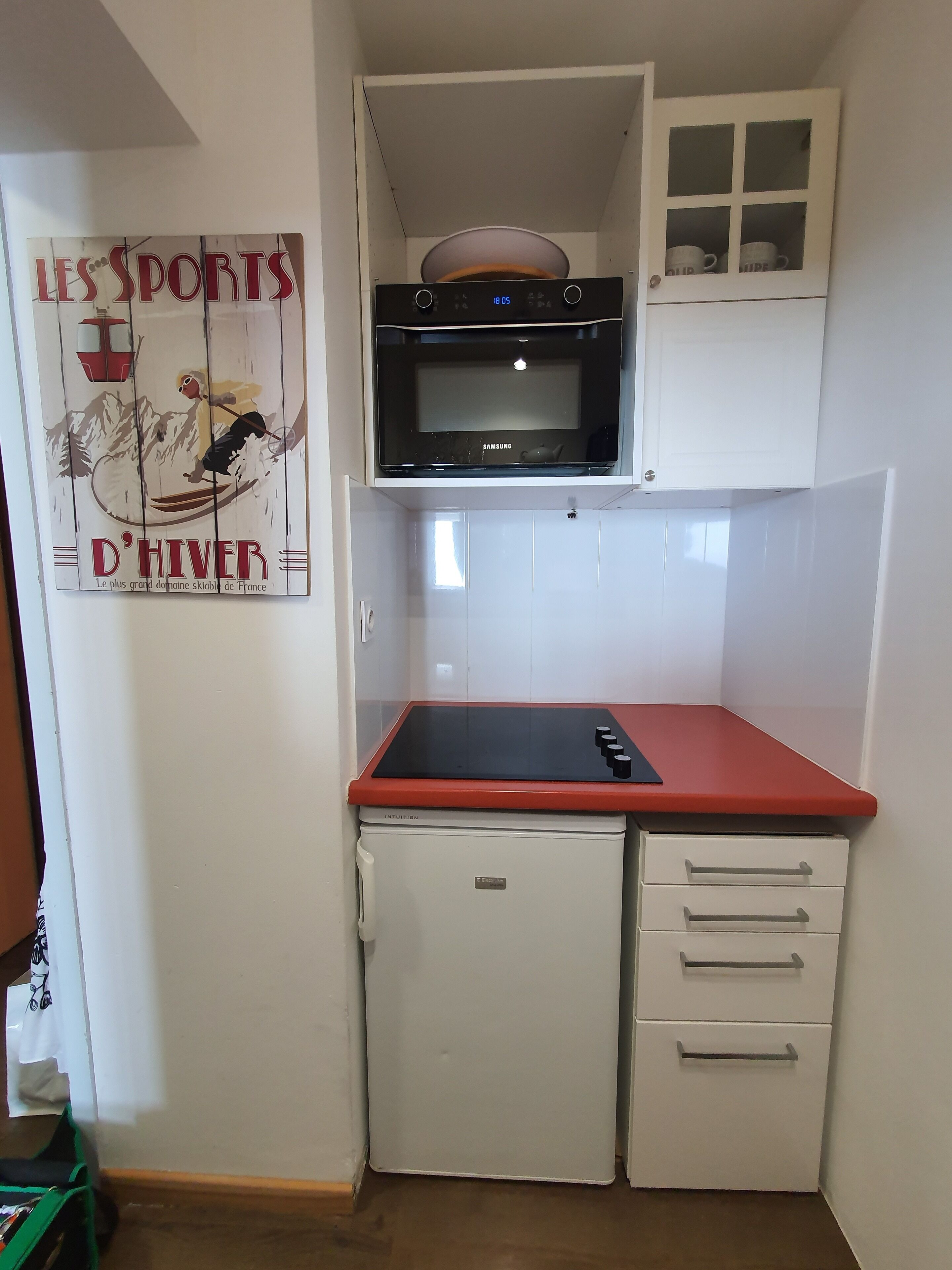 A compact kitchen with a microwave, a small refrigerator, and a sink.