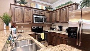 A kitchen with granite countertops, stainless steel appliances, and wooden cabinets. - Long Weekend | Guadalupe Riverfront | Downtown Gruene | Pool (New Braunfels)