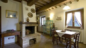 Un coin repas rustique avec une cheminée en pierre, des poutres en bois et une table dressée pour deux personnes.