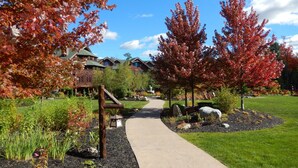 A pathway leading to a lodge with a well-maintained garden and autumn foliage.