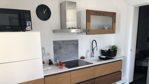 A modern kitchen with a microwave, sink, and a clock on the wall. - Studio apartment two beds (Marina di Palma)