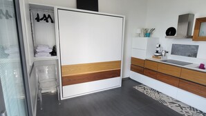 A modern bedroom with a large bed, a wardrobe, a desk, and a chair. - Studio apartment two beds (Marina di Palma)