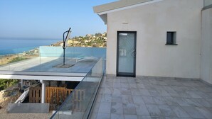A modern building with a glass balcony overlooking a coastal area. - Studio apartment two beds (Marina di Palma)