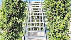 A white wooden staircase leading up to a white railing, surrounded by lush green foliage. - MB Hostels Premium Eco (Nerja)