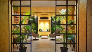 A modern interior with a central seating area, surrounded by bookshelves and potted plants. - MB Hostels Premium Eco (Nerja)