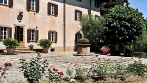 Un edificio con numerose finestre e un cortile con piante e fiori in vaso.