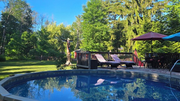 A swimming pool with a deck, lounge chairs, and a wooden deck area.