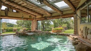 Un'area piscina con acqua cristallina, travi in legno e elementi in pietra.