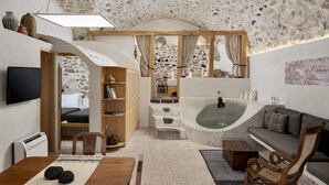 Une pièce chaleureuse avec un plafond en pierre, une baignoire, un canapé et un téléviseur.