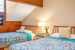 A bedroom with two beds, wooden headboards, a nightstand with a lamp, and a small table with decorative items. - Cozy Ozarks Escape Near Branson ~ Perfect for Couples & Families (Branson)
