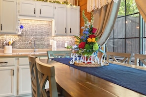 Un coin repas avec une table en bois, des chaises et une pièce maîtresse décorée avec des lettres ou des mots.