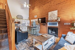 A cozy living room with a fireplace, a dining area, and a kitchen.