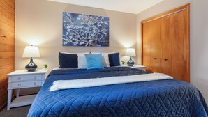 Een slaapkamer met een groot bed, twee nachtkastjes met lampen, een kledingkast en een aan de muur hangend schilderij.