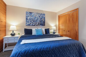 Une chambre à coucher avec un grand lit, deux tables de chevet avec des lampes, une armoire et un tableau accroché au mur.