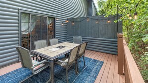 Een terras met een tafel en stoelen, een houten terras en een uitzicht op een huis met gevelbekleding.