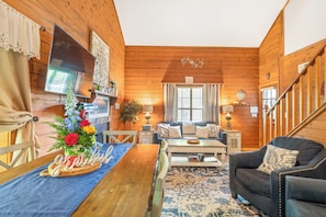L’intérieur d’un chalet accueillant, avec un plancher en bois, un canapé, une table à manger et un escalier.