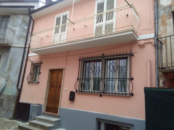 Un bâtiment à deux étages doté d’un balcon, d’une porte en bois et de fenêtres grillagées.