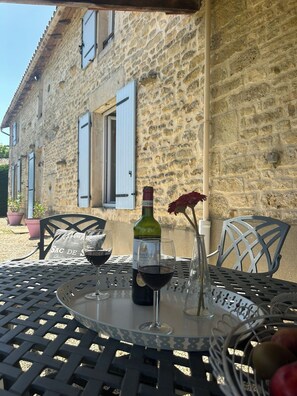 A stone building with a table set for a meal, featuring a bottle of wine and glasses.