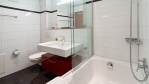 Un baño moderno con lavamanos, inodoro y bañera blancos.