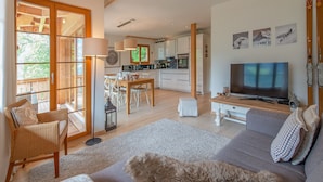 Una sala de estar amplia con un sofá, una televisión y un comedor con una mesa y sillas.