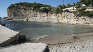 Eine Küstenlandschaft mit einer felsigen Klippe, klarem Wasser und Gebäuden an der Klippe.