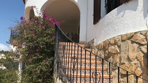 Ein Gebäude mit einer Steintreppe, einer weißen Fassade und einem roten Ziegeldach.