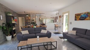 Un grand salon comprenant deux canapés, une table basse et une cuisine à l’arrière-plan.